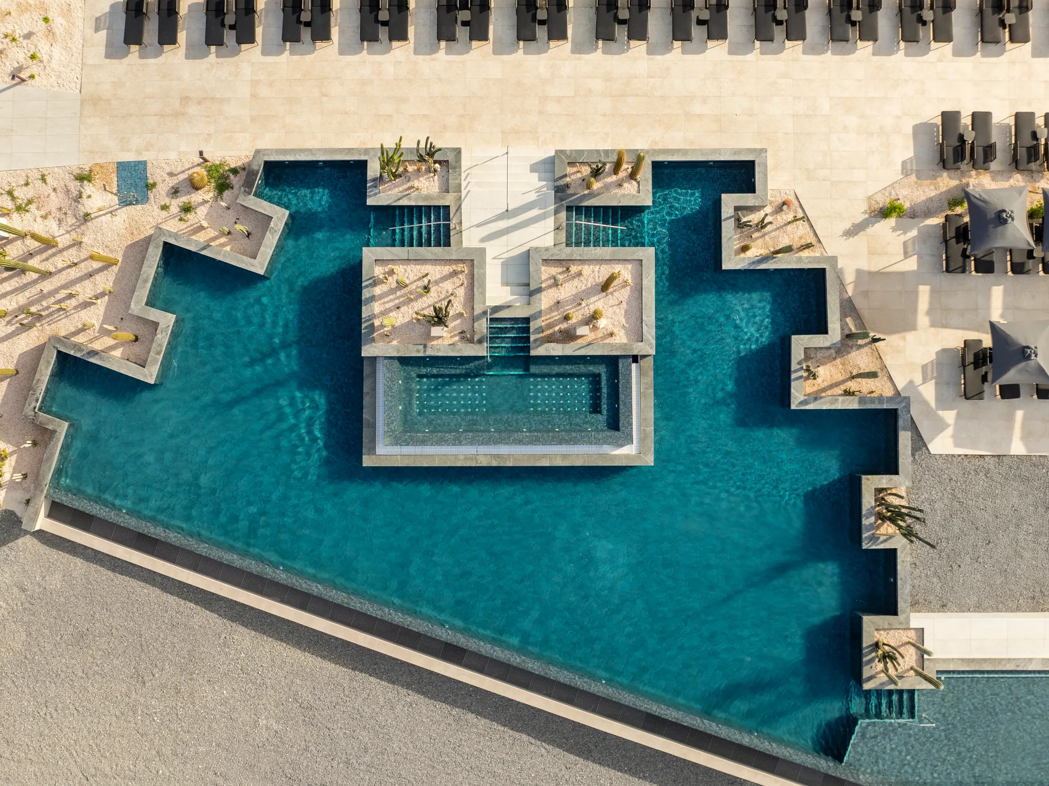 Overhead view of geometric pool design and lounge areas at Secrets Baby Beach Aruba.
