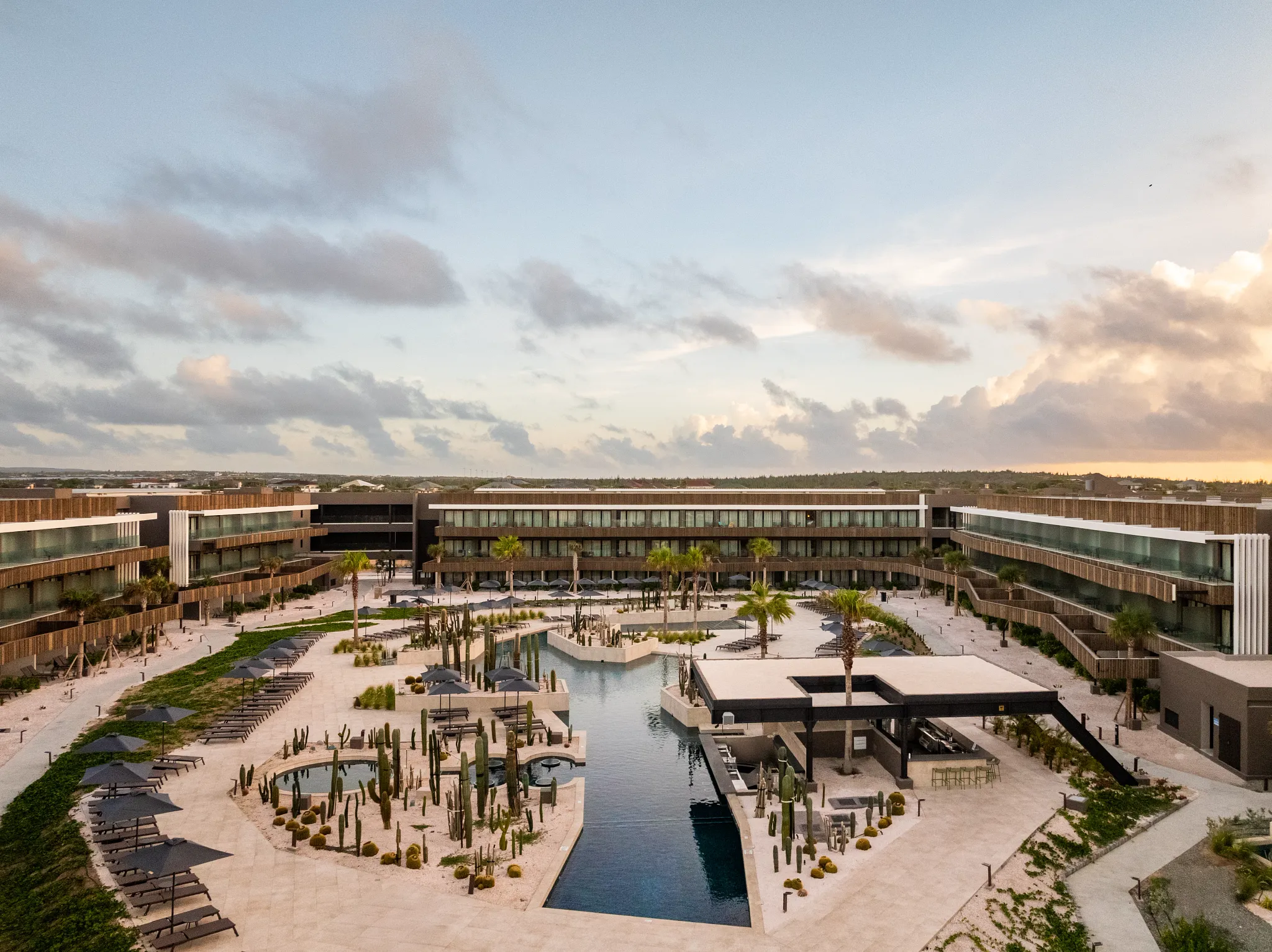 Geometric central pool courtyard at Secrets Baby Beach Aruba surrounded by palm trees and modern architecture.