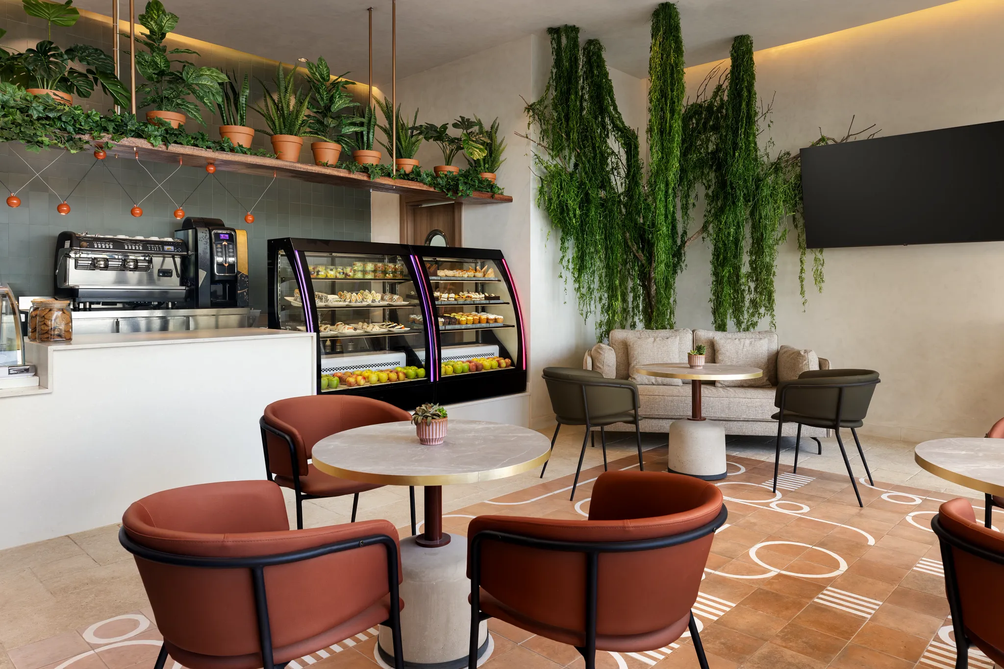 Coco Café at Secrets Baby Beach Aruba featuring a modern coffee bar, pastry display case, and cozy indoor seating with lush greenery décor.