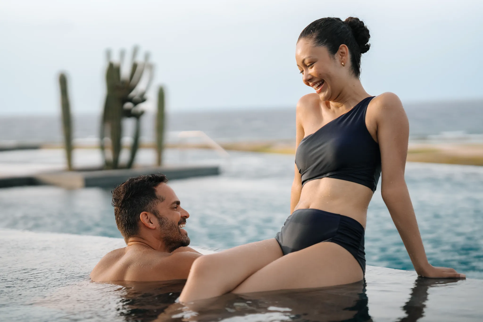 Couple enjoying an infinity pool overlooking the Caribbean Sea at Secrets Baby Beach Aruba.