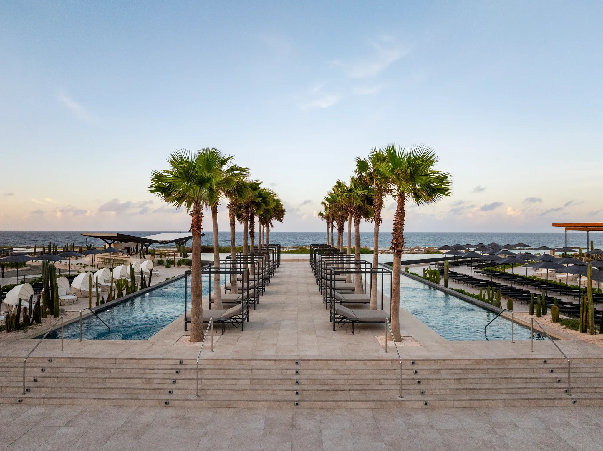 Modern infinity pool terrace at sunset with ocean views at Secrets Baby Beach Aruba.