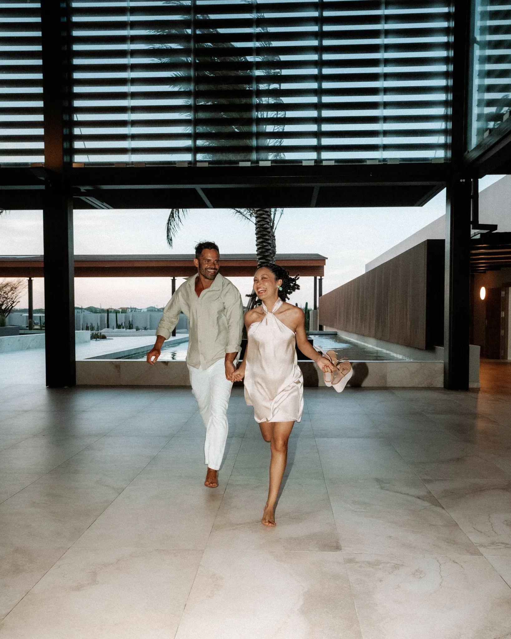 Couple walking hand in hand through the illuminated grounds of Secrets Baby Beach Aruba at night.