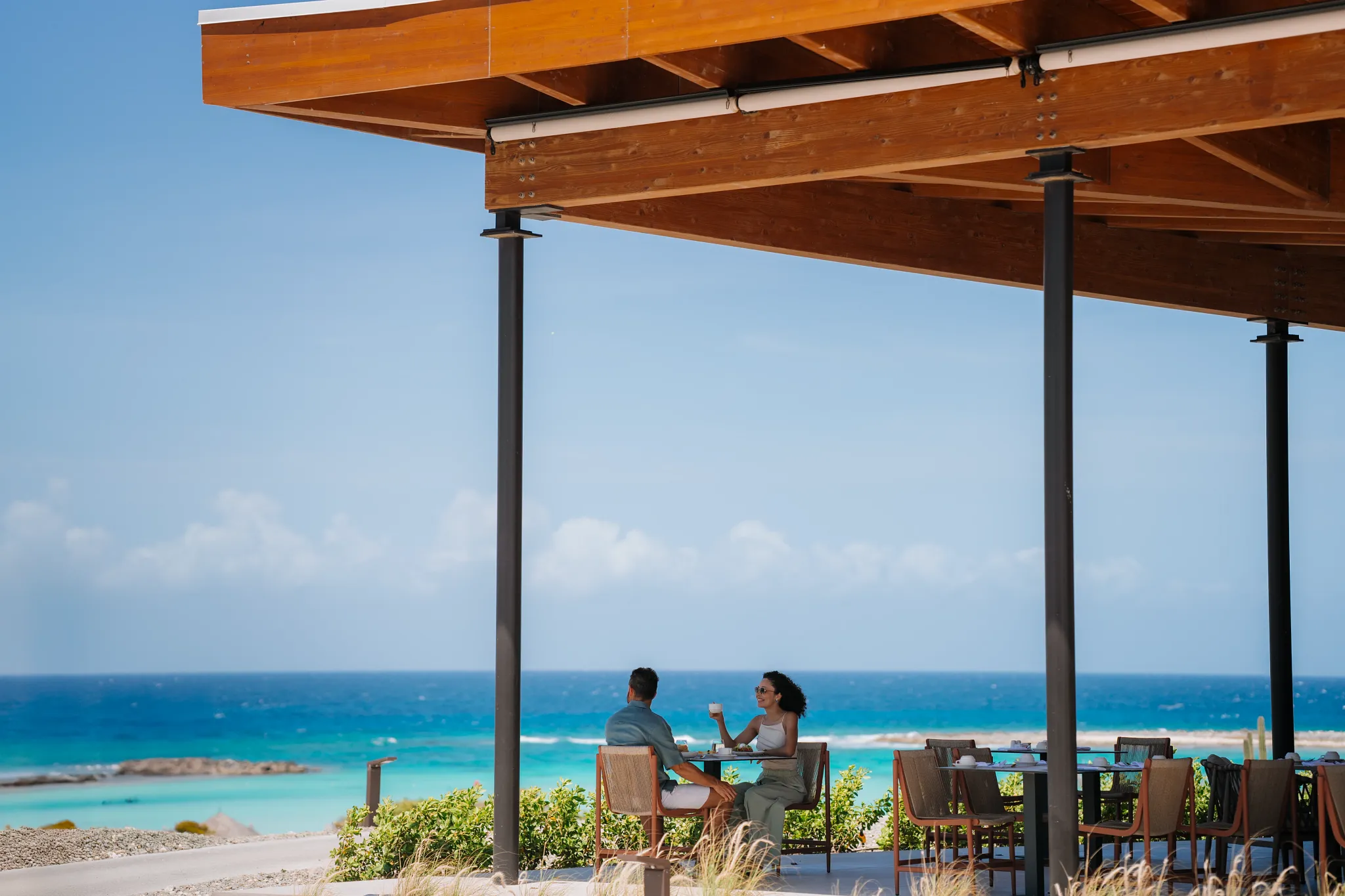 Couple dining outdoors with panoramic ocean views at Secrets Baby Beach Aruba.