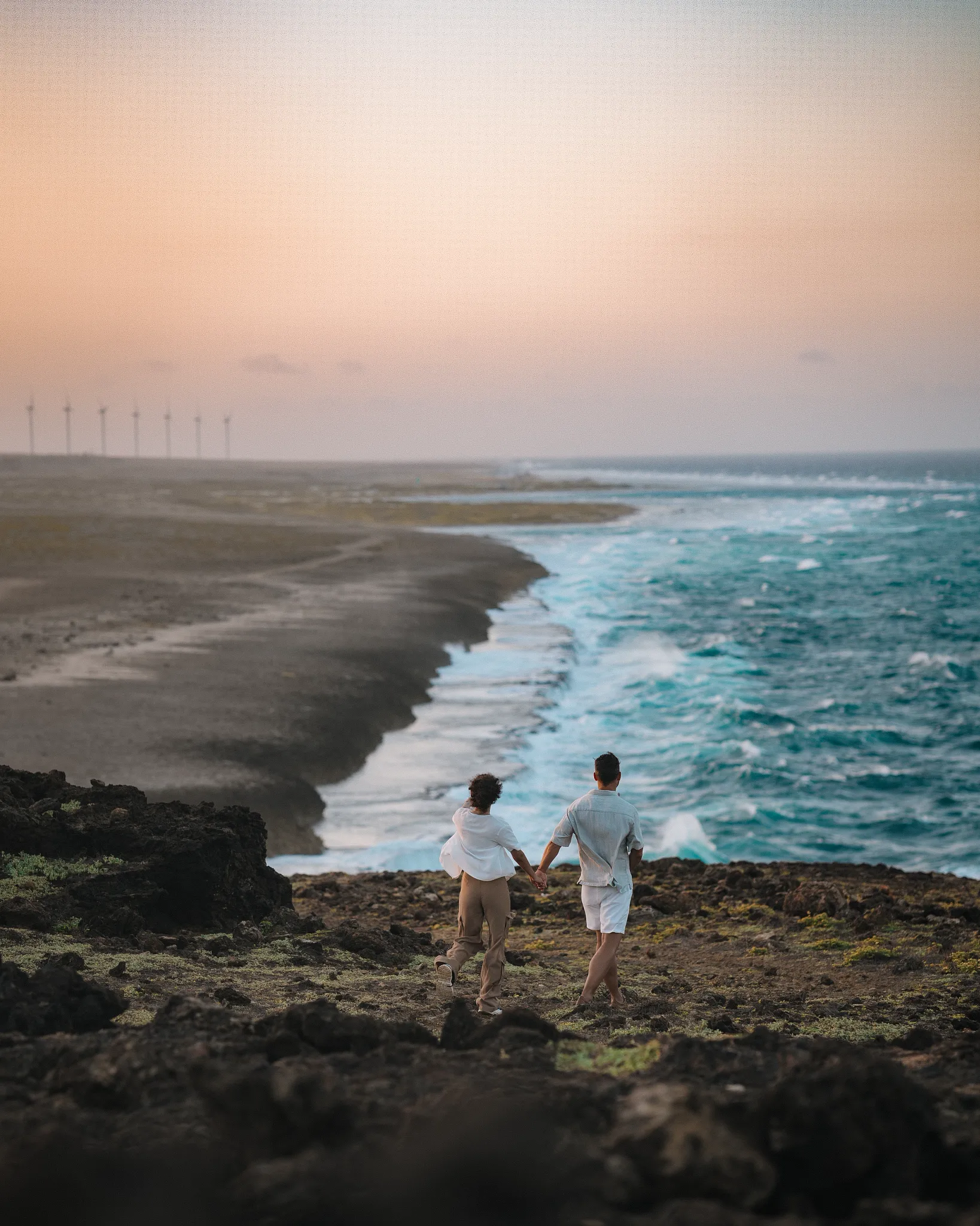 Couple exploring Aruba’s rugged coastline at sunset near Secrets Baby Beach Aruba.