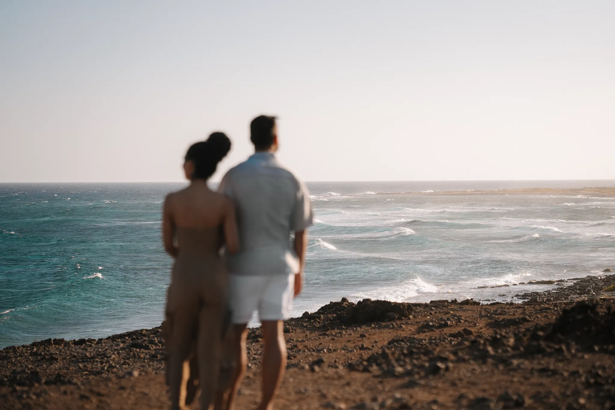 Couple standing together overlooking turquoise Caribbean waters at sunset in Aruba.